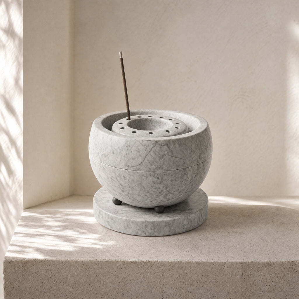 Nimbus natural stone incense holder styled on a quiet stone surface in soft daylight.