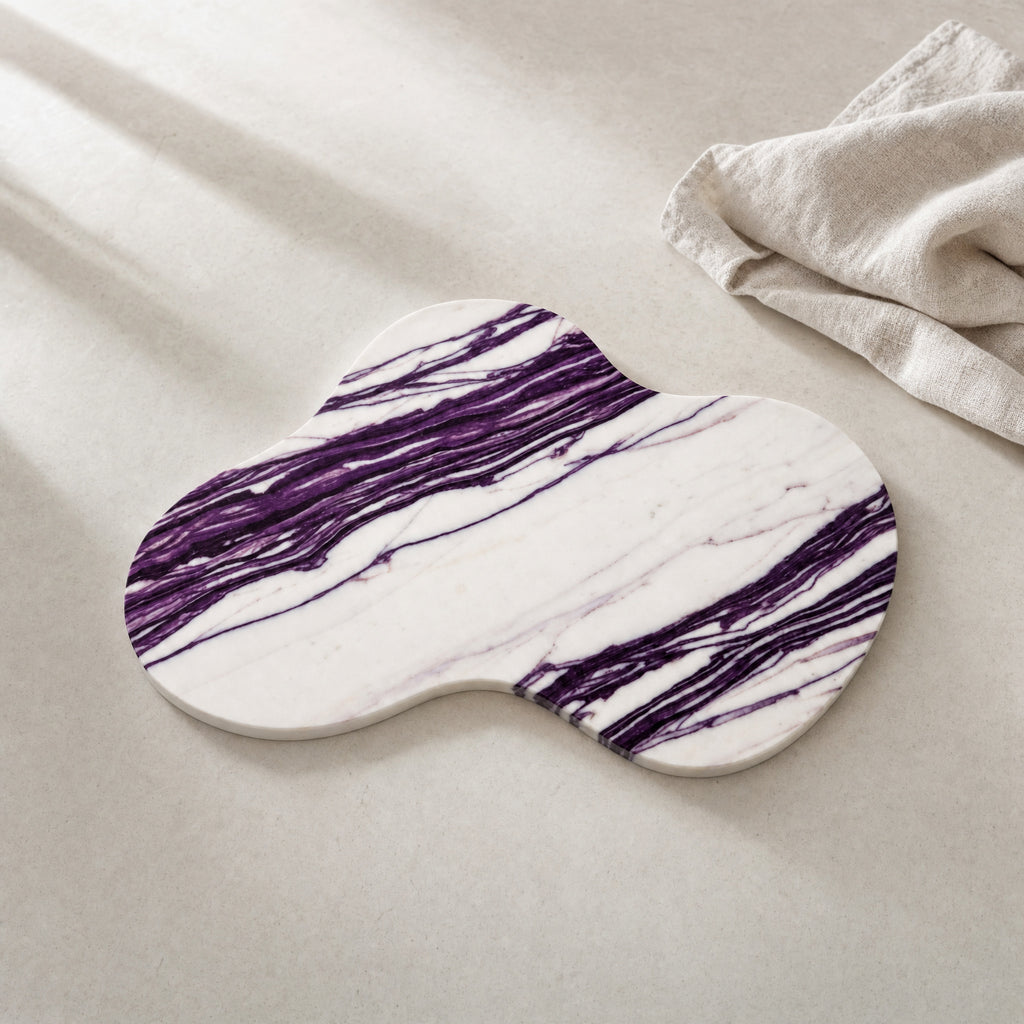 Nuvola purple-veined natural stone serving board on a restrained warm-white table.