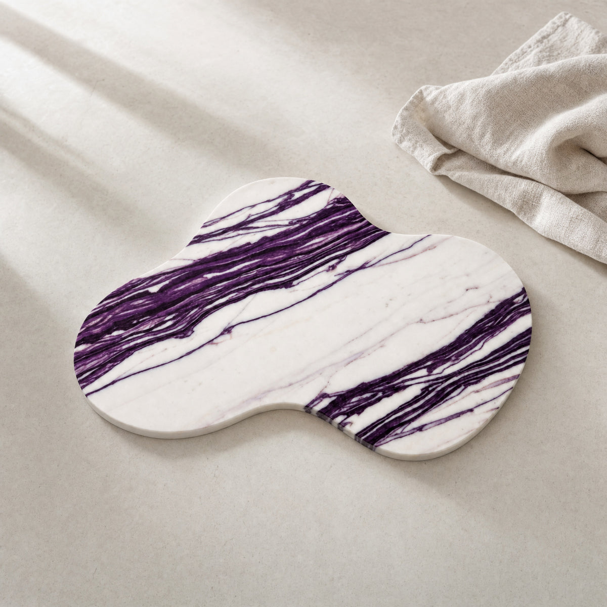 Nuvola purple-veined natural stone serving board on a restrained warm-white table.